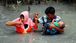 Rohingya refugees carry their child as they walk through water after crossing border by boat through the Naf River in Teknaf, Bangladesh, September 7, 2017. REUTERS/Mohammad Ponir Hossain