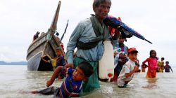A Rohingya refugee man pulls a child as they walk to the shore after crossing the Bangladesh-Myanmar border by boat through the Bay of Bengal in Shah Porir Dwip, Bangladesh, September 10, 2017. REUTERS/Danish Siddiqui