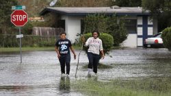 Residents walk through flood waters left in the wake of Hurricane Irma in a suburb of Orlando, Florida, U.S., September 11, 2017. REUTERS/Gregg Newton