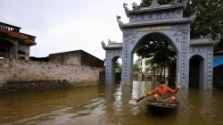 A boy paddles a boat past a flooded village's gate after a heavy rain caused by a tropical depression in Hanoi, Vietnam October 16, 2017.