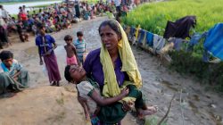 A Rohingya refugee woman who crossed the border from Myanmar a day before, carries her daughter and searches for help as they wait to receive permission from the Bangladeshi army to continue their way to the refugee camps, in Palang Khali, Bangladesh October 17, 2017. REUTERS/Jorge Silva