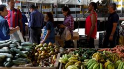 People line up to pay for their fruits and vegetables at a street market in Caracas, Venezuela November 3, 2017.