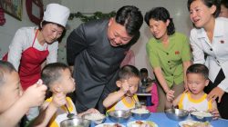 North Korean leader Kim Jong Un smiles as children eat during his visit to the Pyongyang Orphanage on International Children's Day in this undated photo released by North Korea's Korean Central News Agency (KCNA) in Pyongyang