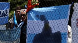 People stand next to a bouquet of flowers and banners in support of the 44 crew members of the missing at sea ARA San Juan submarine, outside an Argentine naval base in Mar del Plata, Argentina November 25, 2017.