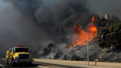 A fire crew passes a burning home during a wind-driven wildfire in Ventura.