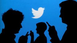 People holding mobile phones are silhouetted against a backdrop projected with the Twitter logo in this illustration picture taken in Warsaw September 27, 2013.