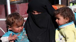 A Syrian woman and her children wait for food aid in front of an humanitarian aid distrubition center in Syrian border town of Jarablus, Syria, December 13, 2017.
