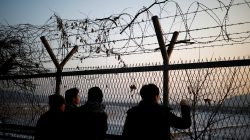 People look toward the north through a barbed-wire fence near the militarized zone separating the two Koreas, in Paju, South Korea, December 21, 2017.