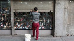 A worker closes the security shutter of a window display at a shoes store in downtown Caracas, Venezuela January 16, 2018.