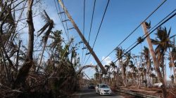 Cars drive under a partially collapsed utility pole, after the island was hit by Hurricane Maria in September, in Naguabo, Puerto Rico October 20, 2017.