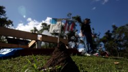 Faded U.S. flag and Puerto Rican flag are stuck into a mound of earth near the remains of Angel Colon's house after it was destroyed during Hurricane Maria in September 2017, in Comerio, Puerto Rico