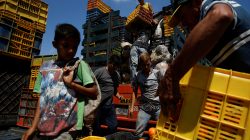 A child looks at a basket filled with mandarins while workers load merchandise into Humberto Aguilar's truck at the wholesale market in Barquisimeto, Venezuela January 30,