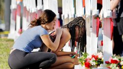 A senior at Marjory Stoneman Douglas High School weeps in front of a cross and Star of David for shooting victim Meadow Pollack while a fellow classmate consoles her at a memorial by the school in Parkland, Florida, U.S. February 18, 2018. REUTERS/Jonathan Drake