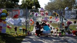 People put flowers among other mementoes at the fence of the Marjory Stoneman Douglas High School, after the police security perimeter was removed, following a mass shooting in Parkland, Florida, U.S., February 18, 2018. REUTERS/Carlos Garcia Rawlins