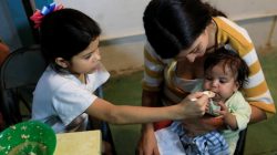 Osiris (L), daughter of Viviana Colmenares (C), feeds her sister Ornella in a community diner at the slum of Petare in Caracas, Venezuela February 22, 2018. Picture taken February 22, 2018. REUTERS/Marco Bello