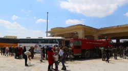 People, who were evacuated from the two rebel-besieged Shi'ite villages of al-Foua and Kefraya, stand near buses at insurgent-held al-Rashideen, Aleppo province, Syria April 19, 2017. REUTERS/Ammar Abdullah
