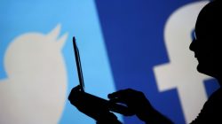 FILE PHOTO - A man is silhouetted against a video screen with a Twitter and a Facebook logo as he poses with a laptop in this photo illustration taken in the central Bosnian town of Zenica, August 14, 2013. REUTERS/Dado Ruvic