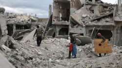 People walk on rubble of damaged buildings in the besieged town of Douma, Eastern Ghouta, in Damascus, Syria March 30, 2018. REUTERS/Bassam Khabieh