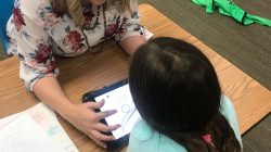 Former Oklahoma teacher Chelsea Price, 34, helps a 2nd grade student with an assignment on an iPad in her classroom in Grapevine, Texas, U.S., April 4, 2018. Courtesy Chelsea Price/Handout via REUTERS