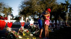 Adin Chistian (16), student of the Marjory Stoneman Douglas High School, embraces his mother Denyse, next to the crosses and Stars of David placed in front of the fence of the school to commemorate the victims of a shooting, in Parkland, Florida, U.S., February 19, 2018. REUTERS/Carlos Garcia Rawlins