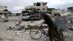 A man walks with his bicycle at a damaged site in the besieged town of Douma, Eastern Ghouta, in Damascus, Syria March 30, 2018. REUTERS/Bassam Khabieh