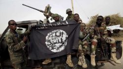 FILE PHOTO: Nigerian soldiers hold up a Boko Haram flag that they had seized in the recently retaken town of Damasak, Nigeria, March 18, 2015. REUTERS/Emmanuel Braun/File Photo