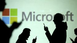 Silhouettes of mobile users are seen next to a screen projection of Microsoft logo in this picture illustration taken March 28, 2018. REUTERS/Dado Ruvic/Illustration