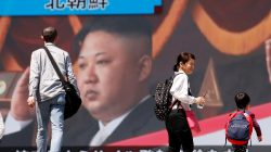 People walk past a street monitor showing North Korea's leader Kim Jong Un in a news report about North Korea's announcement, in Tokyo, Japan, April 21, 2018. REUTERS/Toru Hanai