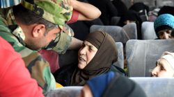A soldier loyal to Syria's President Bashar al Assad forces talks to a woman in a bus after they were released by militants from Idlib, Syria May 1, 2018. SANA/Handout via REUTERS