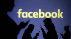FILE PHOTO: Silhouettes of mobile users are seen next to a screen projection of Facebook logo in this picture illustration taken March 28, 2018. REUTERS/Dado Ruvic/Illustration/File Photo