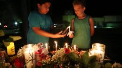 Christian Cardenas 10, helps Jaydon Johnson 8, light a candle during a vigil for the victims of a shooting at Santa Fe High School that left several dead and injured in Santa Fe, Texas, U.S., May 18, 2018. REUTERS/Pu Ying Huang