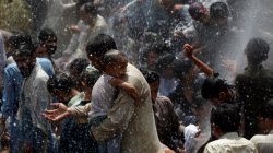 Men and children cool off from the heatwave, as they are sprayed with water jetting out from a leaking water pipeline in Karachi, Pakistan May 22, 2018. REUTERS/Akhtar Soomro