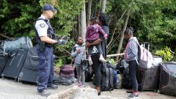 FILE PHOTO: A family who identified themselves as being from Hait, are confronted by a Royal Canadian Mounted Police (RCMP) officer as they try to enter into Canada from Roxham Road in Champlain, New York, U.S., August 7, 2017. REUTERS/Christinne Muschi/File Phot