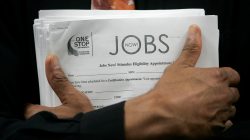 FILE PHOTO: A man carrying a stack of job listings listens to a discussion at the One Stop employment center in San Francisco, California, August 12, 2009. REUTERS/Robert Galbraith/File Photo