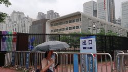 A woman shields herself from the rain as she walks past U.S. Consulate in Guangzhou, China June 7, 2018. REUTERS/Sue-Lin Wong
