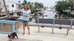 Terri Metter, 50, and her Boston Terrier Nikki stand in front of a debris-filled canal in the RV park where she has been living in a FEMA trailer since November 2017, in Marathon, Florida, U.S., June 10, 2018. REUTERS/Zach Fagenson