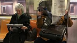 A couple of people ride the subway as they read newspapers as the train pulls into the Times Square stop in Manhattan, New York, U.S. February 17, 2017. REUTERS/Carlo Allegri