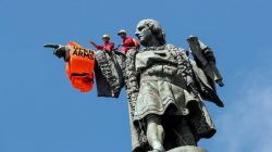 FILE PHOTO: Activists from the Spanish Proactiva Open Arms charity place a life jacket on the Christopher Columbus statue after the Open Arms rescue boat arrived at a port in Barcelona, Spain, carrying migrants rescued off Libya, July 4, 2018. REUTERS/Albert Gea/File Photo