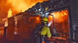 Santa Barbara County Firefighter spray water on flames at a home at the site of a wildfire in Goleta, California, U.S., July 6, 2018 in this image released on social media. Mike Eliason/Santa Barbara County Fire/via REUTERS