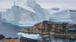 A giant iceberg is seen behind an Innaarsuit settlement, Greenland July 12, 2018. Picture taken July 12, 2018. Ritzau Scanpix/Karl Petersen/ via REUTERS