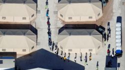 FILE PHOTO: Immigrant children, many of whom have been separated from their parents under a new "zero tolerance" policy by the Trump administration, are shown walking in single file between tents in their compound next to the Mexican border in Tornillo, Texas. REUTERS/Mike Blake