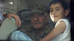 A fighter loyal to President Bashar al Assad and a child are seen in a bus as they are evacuated from the villages of al-Foua and Kefraya, Syria July 19, 2018. REUTERS/Khalil Ashawi