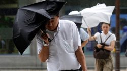 Passersby using an umbrella struggle against a heavy rain and wind as Typhoon Shanshan approaches Japan's mainland in Tokyo, Japan August 8, 2018. REUTERS/Toru Hanai