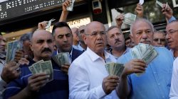 Businessmen holding U.S. dollars stand in front of a currency exchange office in response to the call of Turkish President Tayyip Erdogan on Turks to sell their dollar and euro savings to support the lira, in Ankara, Turkey August 14, 2018. REUTERS/Umit Bektas
