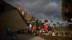 An empty chair is seen in front of flowers and mementoes placed on a fence to commemorate the victims of the mass shooting at Marjory Stoneman Douglas High School, in Parkland, Florida, U.S., February 20, 2018. REUTERS/Carlos Garcia Rawlins