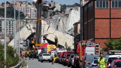 Firefighters and rescue workers stand at the site of a collapsed Morandi Bridge in the port city of Genoa, Italy August 15, 2018. REUTERS/Stefano Rellandini