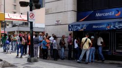 People line up to withdraw cash from an automated teller machine (ATM) outside a Banco Mercantil branch in Caracas, Venezuela August 17, 2018. REUTERS/Marco Bello