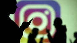 FILE PHOTO: Silhouettes of mobile users are seen next to a screen projection of Instagram logo in this picture illustration taken March 28, 2018. REUTERS/Dado Ruvic/Illustration