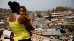 FILE PHOTO: Ysamar Figueroa carrying her son Saniel, looks at the damage in the neighbourhood after the area was hit by Hurricane Maria, in Canovanas, Puerto Rico September 26, 2017. REUTERS/Carlos Garcia Rawlins/File Photo