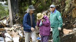 A woman (C) wipes her tears after her missing father was found at an area damaged by a landslide caused by an earthquake in Atsuma town, Hokkaido, northern Japan, in this photo taken by Kyodo September 7, 2018. Kyodo/via REUTERS
